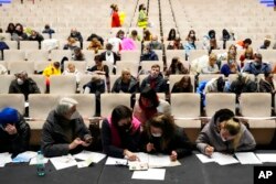 FILE - Refugees that fled the war in Ukraine fill in the paperwork to get registered, at the congress center in Prague, Czech Republic, March 15, 2022.
