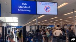 FILE - A sign warns travelers not to bring guns through the Transportation Security Administration checkpoint at Orlando International Airport in Orlando, Florida, April 23, 2022.