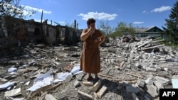 Tatyana Skrypnikova, 60, who suffered light shrapnel wounds, stands among the debris of her neighbors' house, destroyed following a shelling in Kharkiv oblast, on Aug. 17, 2023, amid the Russian invasion of Ukraine. 
