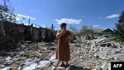 ৬০ বছর বয়সী তাতায়ানা স্ক্রিপনিকোভা যিনি হালকা আঘাতে ভুগেছিলেন, তিনি তার প্রতিবেশীদের বাড়ির ধ্বংসাবশেষের মধ্যে দাঁড়িয়ে আছেন। খারকিভে গোলাগুলির পরে ধ্বংস হয়ে গেছে এই বাড়িঘর। ১৭ আগস্ট, ২০২৩। 