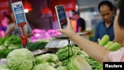 FILE - A customer scans a QR code to pay for vegetables at a morning market in Beijing, Aug. 9, 2023. Indonesia will expand QR systems in part to increase tourism from China, where that payment system is common.