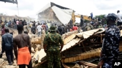 People gather at the scene of a collapsed two-story building in Jos, Nigeria, July, 12, 2024.