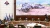 Russian Defense Minister Sergei Shoigu, in front of the flags, speaks with high-level officers in Moscow, May 24, 2023. Damaged allegedly U.S.-made vehicles are seen after fighting in Russia's Belgorod region. (Russian Defense Ministry Press Service via AP)