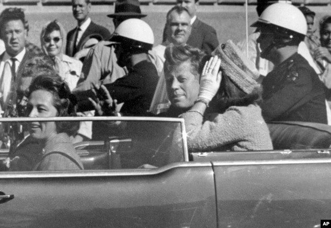 FILE - President John F. Kennedy waves from his car in a motorcade approximately one minute before he was shot, Nov. 22, 1963, in Dallas. (AP Photo/Jim Altgens, File)