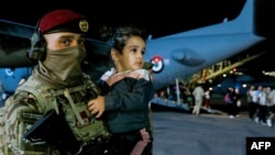 A soldier carries a child as people evacuated from Sudan disembark from an aircraft at a military airport in Amman on April 24, 2023.