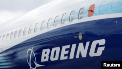 Logo Boeing tampak di samping pesawat Boeing seri 737 Max di pameran dirgantara Farnborough International Airshow, di Farnborouh, Inggris, 20 Juli 2022. (Foto: Peter Cziborn/Reuters)