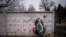 FILE: A wreath leans against a shrapnel-damaged wall in the cemetery where a funeral for an officer of the 93rd Ukrainian brigade was being held in Bucha, near Kyiv, Ukraine. Fri. Feb. 17, 2023. Bucha was the scene of documented mass killings considered to be War Crimes. 