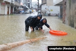 中国湖南省长沙市暴雨中的街道，工人冒雨疏通下水道。（2024年6月24日）