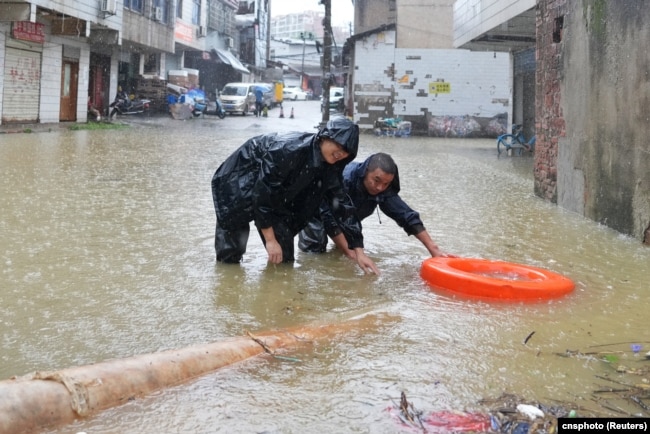 中国湖南省长沙市暴雨中的街道，工人冒雨疏通下水道。（2024年6月24日）