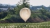 FILE - A balloon believed to have been sent by North Korea, carrying what appeared to be trash and excrement, is seen over a field at Cheorwon, South Korea, May 29, 2024. The military in Seoul said on Aug. 10 that the North is again flying trash balloons. (Yonhap via Reuters)