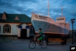 A boy rides a bicycle in what used to be the main port of Aralsk, Kazakhstan, before the Aral Sea dried up, July 4, 2023.
