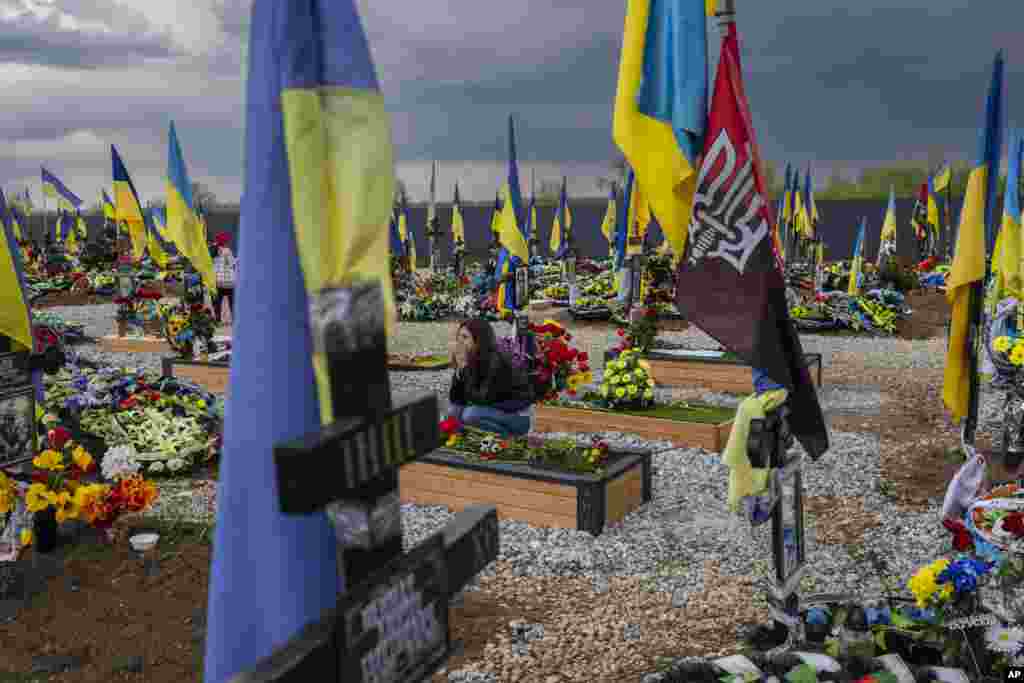 Жена го посетува гробот на нејзиниот пријател, украински војник, на гробиштата Криви Рих во источна Украина.