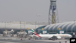 FILE - An Emirates jet waits at the gate as another prepares to land in Dubai, United Arab Emirates, on Aug. 17, 2022, shortly before the airline suspended flights to Nigeria. Nigerian authorities on Sept. 12, 2023, announced that the UAE would lift a year-old visa ban.