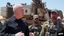 FILE - Israeli Defense Minister Yoav Gallant stands with soldiers by a self-propelled artillery howitzer during a visit to a position along the border with the Gaza Strip in southern Israel near Rafah, May 7, 2024. (Photo by Israeli Army/AFP) 