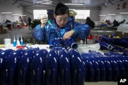 Seorang pekerja sedang merakit alat musik di sebuah pabrik di Wuqiang County, di Provinsi Hebei, China, 23 Februari 2023. (Foto: Mu Yu/Xinhua via AP)