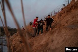 After wading across the Rio Grande River into Texas on Christmas, Diely Hernandez, 39, who injured her foot during her family’s three-month trip from Venezuela, gets help crossing a riverbank by her husband Deibyd Ramos, 46, and another migrant