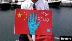 Seorang pria etnis Uighur memegang plakat saat berpartisipasi dalam protes terhadap China untuk memperingati 14 tahun kerusuhan Urumqi di Istanbul, Turki, 5 Juli 2023. (Foto: Reuters)