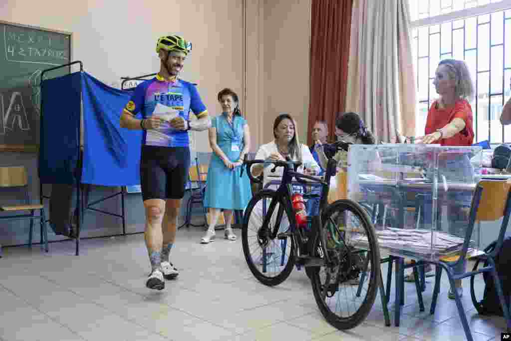 A biker prepares to cast a ballot inside a classroom which is used as a voting station during the European Elections in Athens, Greece, June 9, 2024.