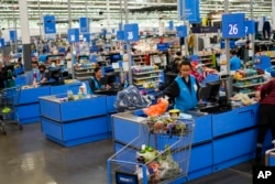 FILE - Cashiers process purchases at a Walmart Supercenter in North Bergen, N.J., Feb. 9, 2023.