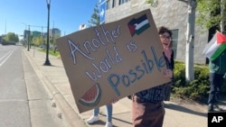 Pro-Palestinian supporters demanding divestment from companies that profit off the Israel-Hamas war hold signs outside as University of Minnesota regents meet, May 10, 2024, in Minneapolis.