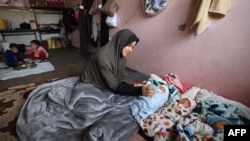 Iman al-Masri, a displaced Palestinian who fled from her home in Beit Hanoun with her family to escape Israeli bombardment, feeds one of her quadruplets &mdash; with the fourth still being treated in hospital &mdash; as they take shelter at a school in Deir al-Balah in the central Gaza Strip.