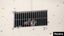 (FILE) Displaced Palestinians who fled their houses due to Israeli strikes look out from a window as they take shelter, in Khan Younis in the southern Gaza Strip, July 24, 2024.