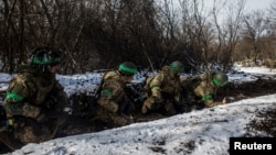 Ukrainian servicemen take cover during a shelling outside the frontline town of Bakhmut, amid Russia's attack on Ukraine, in Donetsk region, Ukraine, Feb. 13, 2023. 