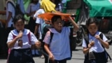 Seorang pelajar menggunakan amplop untuk melindungi dirinya dari terik matahari di Manila pada 2 April 2024. (Foto: AFP)