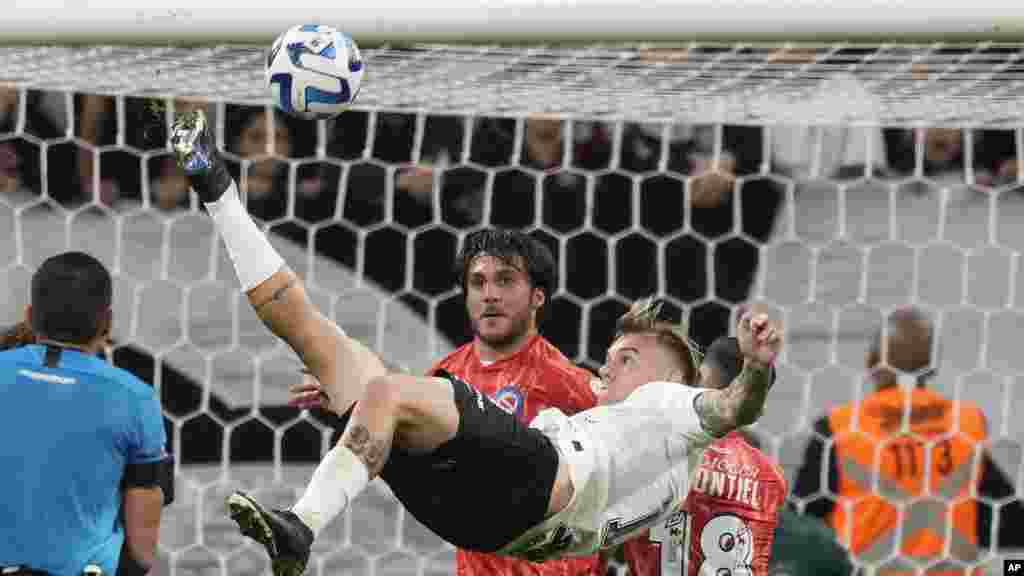 Roger Guedes, del Corinthias de Brasil, realiza un disparo de tijera mientras Kevin Mac Allister, del Argentinos Juniors, de Argentina, y su compañero Santiago Montiel, están atentos a la jugada durante un partido del Grupo E de la Copa Libertadores en Sao Paulo, Brasil, el miércoles 19 de abril de 2023. Foto - Andre Penner.