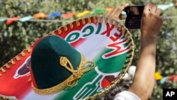 Un hombre con un gran sombrero se toma una foto durante las festividades del Cinco de Mayo en La Placita de Los Ángeles, el lugar donde se fundó la ciudad en 1781, en el centro de Los Ángeles el miércoles 5 de mayo de 2010. (AP Photo/Reed Saxon)