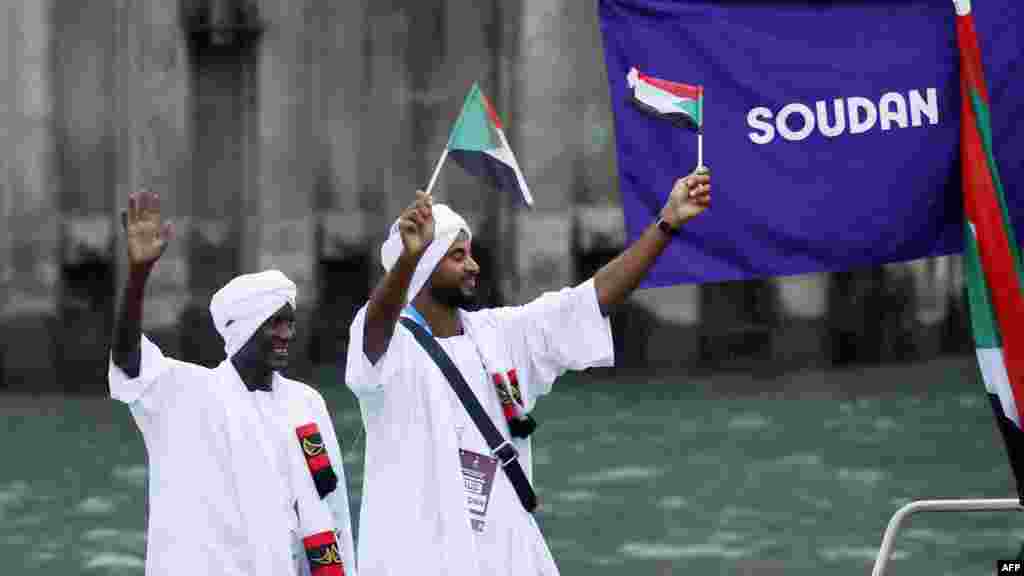 Atlet delegasi Sudan mengibarkan bendera di atas perahu dalam parade terapung di sungai Seine saat upacara pembukaan Olimpiade 2024 di Paris, 26 Juli 2024. (Foto: Clodagh Kilcoyne / POOL / AFP) &nbsp; 