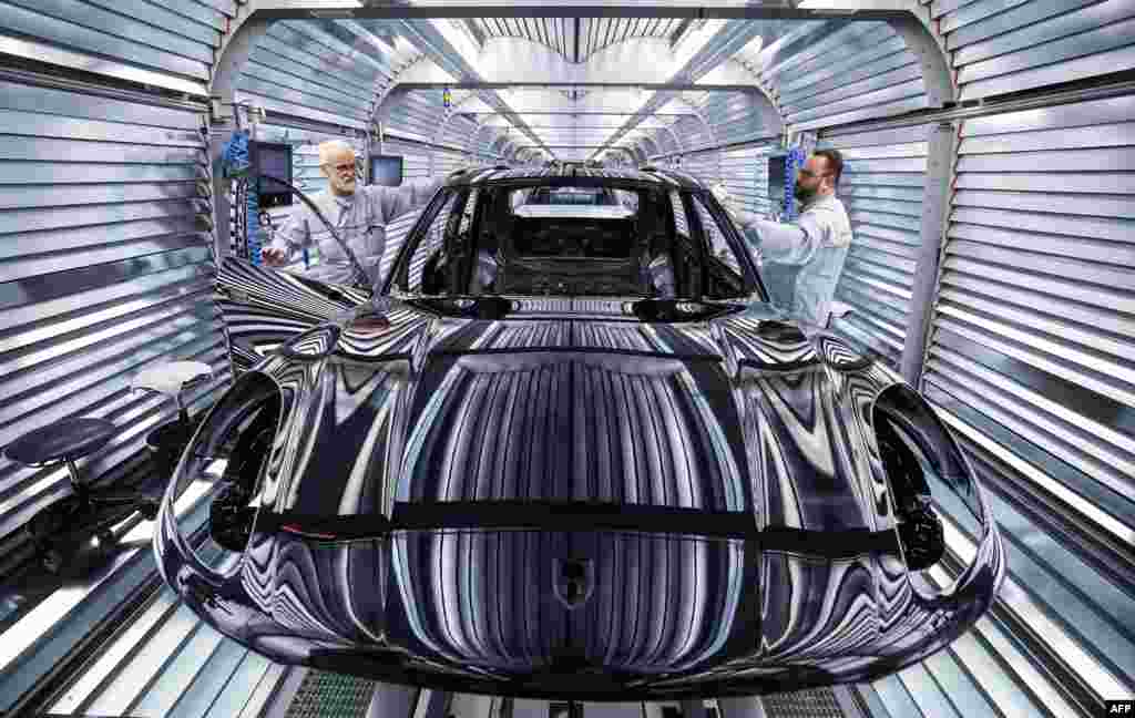 Workers assemble a Porsche Macan model on the production and quality control line of the Porsche plant in Leipzig, eastern Germany, March 11, 2024.