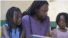 FILE - Ezaius Mkandawire, a Malawian Rastafarian sits with his children in Lilongwe, Jan. 30, 2020. 