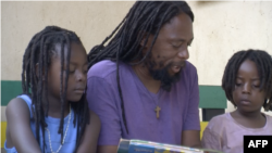 FILE - Ezaius Mkandawire, a Malawian Rastafarian sits with his children in Lilongwe, Jan. 30, 2020. 