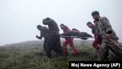 In this photo provided by Moj News Agency, rescue teams members carry body of a victim after a helicopter carrying Iranian President Ebrahim Raisi crashed in Varzaghan, northwestern Iran, May 20, 2024.
