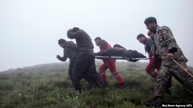 In this photo provided by Moj News Agency, rescue teams members carry body of a victim after a helicopter carrying Iranian President Ebrahim Raisi crashed in Varzaghan, northwestern Iran, May 20, 2024.