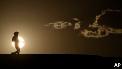 FILE - A person walks along a trail as the sun sets July 16, 2023, in Death Valley National Park, Calif.