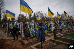 People line up to throw dirt in the grave during the farewell for Ukrainian Capt. Serhii Vatsko in Boiarka, Ukraine, March 29, 2024. Vatsko, killed on the front line of eastern Ukraine on March 24, joined the country's military in 2014.