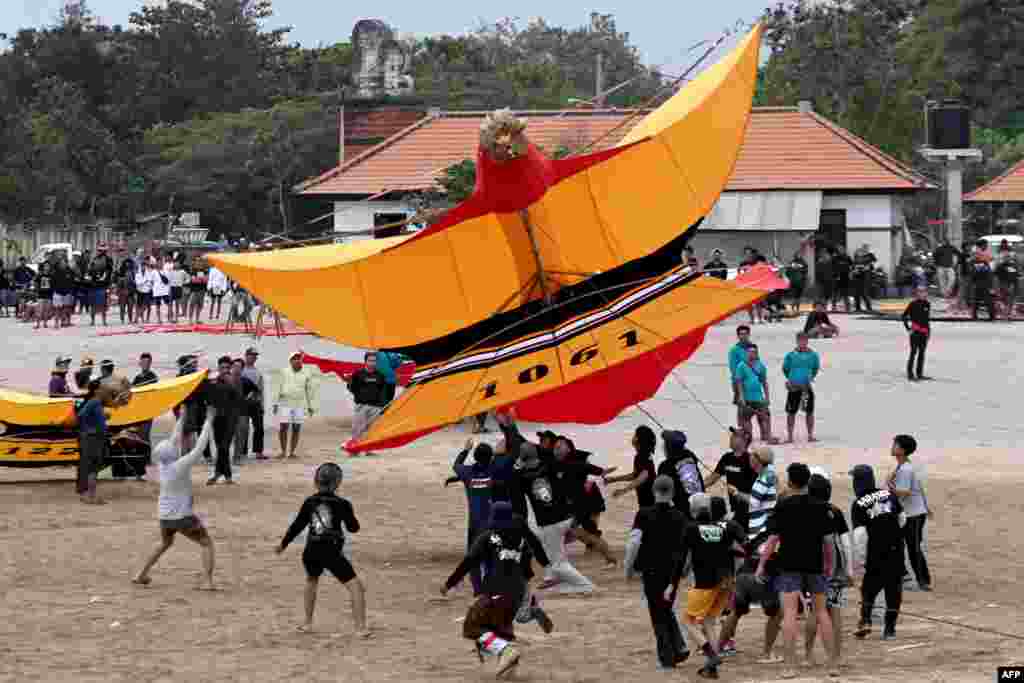 Participants launch a giant kite during the Bali Kite Festival at Mertasari beach in Sanur, Indonesia&#39;s Bali island.