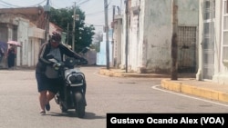 Una mujer empuja su motocicleta apagada en el sector Santa Lucía de Maracaibo, una ciudad venezolana que sufre una aguda escasez de combustible.