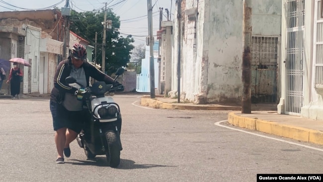 Una mujer empuja su motocicleta apagada en el sector Santa Lucía de Maracaibo, una ciudad venezolana que sufre una aguda escasez de combustible.