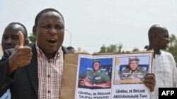 FILE - A supporter of Niger's National Council for the Safeguard of the Homeland (CNSP) holds up a placard with a photo of General Abdourahamane Tiani on in Niamey, Aug. 6, 2023. 