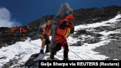 Ngima Tashi Sherpa berjalan sambil menggendong seorang pendaki Malaysia saat menyelamatkannya dari zona kematian di atas kamp empat di Everest, Nepal, 18 Mei 2023. (Foto: Gelje Sherpa via REUTERS)