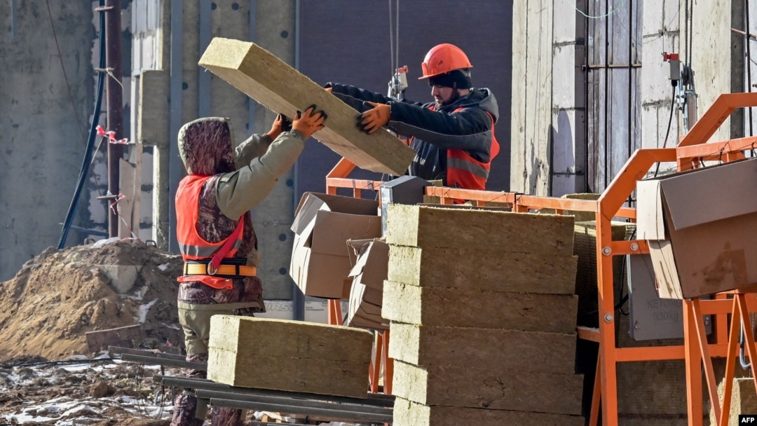 FILE - Laborers work on a construction site in Moscow, March 12, 2021. Thousands of Uzbeks working in Russia now are considering returning home to help with the construction of the "New Tashkent" development projects.