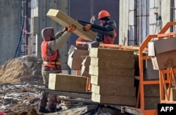 FILE - Laborers work at a housing construction site of Granelle, a Moscow-based developer, in southwest Moscow, Russia, March 12, 2021. For years, Russia has relied on migrant workers to do some of the hardest and worst paying jobs.