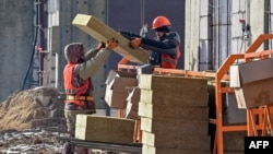 FILE - Laborers work on a construction site in Moscow, March 12, 2021. Thousands of Uzbeks working in Russia now are considering returning home to help with the construction of the "New Tashkent" development projects. 