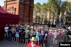 Supporters of Catalan separatist leader Carles Puigdemont, wear straw hats as they form a barrier by linking arms next to a tent where Puigdemont stood, after he returns to Spain from seven years of self-imposed exile, in Barcelona, Aug. 8, 2024
