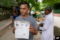 Roadside vendor Shankar Lal shows his government permit to run a stall in New Delhi, India, Thursday, Aug. 24, 2023. Shankar Lal said he hasn't opened his stall, where he sells chickpea curry with fried flatbreads, for three months after authorities told him to move away. "The government doesn't know whether we are dying of hunger or not," Lal said. (AP Photo/Manish Swarup)