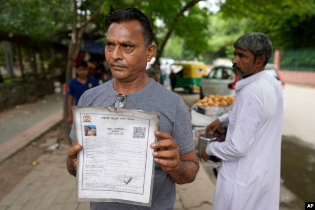 Roadside vendor Shankar Lal shows his government permit to run a stall in New Delhi, India, Thursday, Aug. 24, 2023. Shankar Lal said he hasn't opened his stall, where he sells chickpea curry with fried flatbreads, for three months after authorities told him to move away. "The government doesn't know whether we are dying of hunger or not," Lal said. (AP Photo/Manish Swarup)