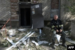 A rescuer rests next to a destroyed residential building following a missile attack in Lugansk, Russian-controlled Ukraine, June 7, 2024.